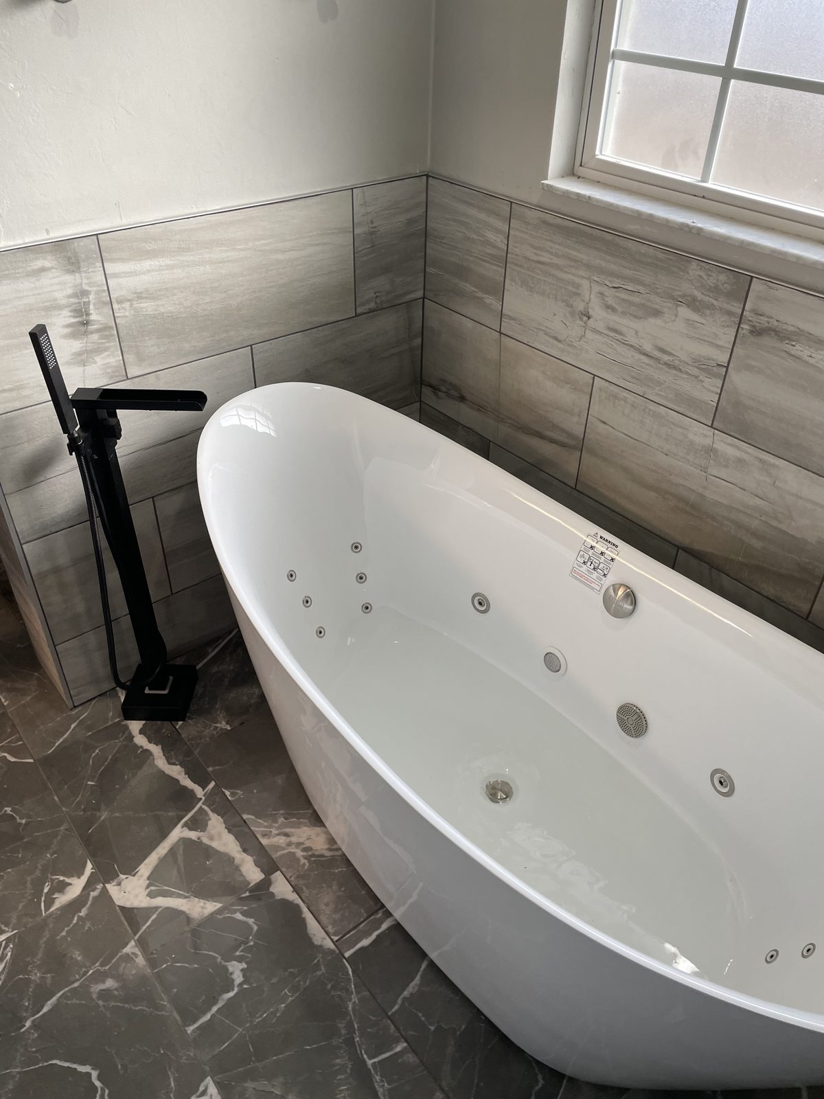White freestanding jetted tub with a black floor-mount filler