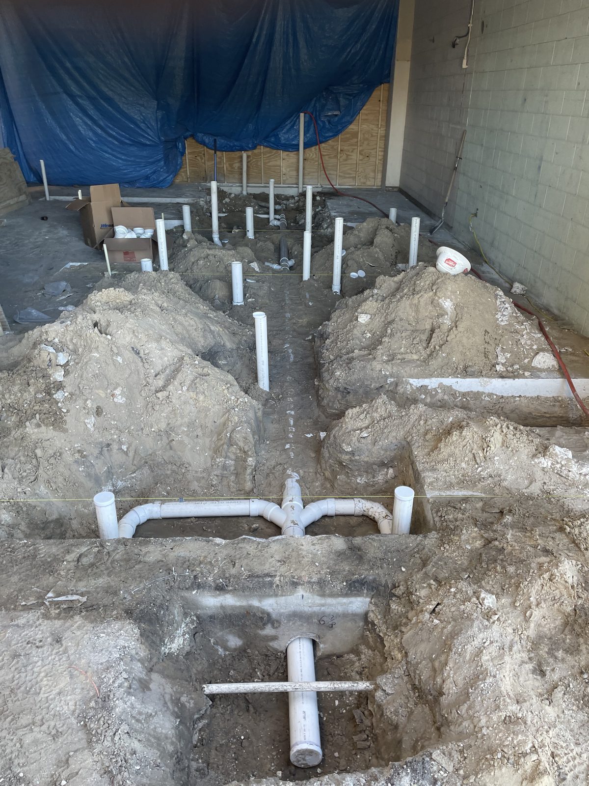 Underground PVC drain rough-in in open trenches before the slab is poured