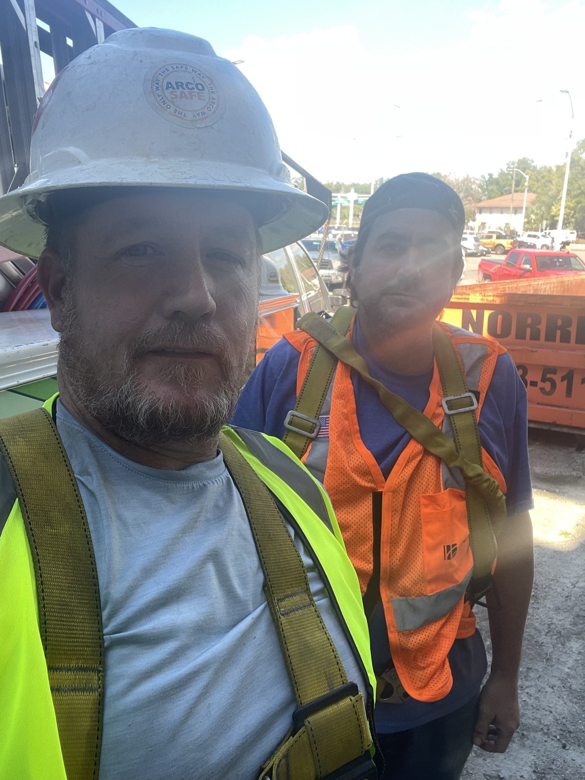 Two Hometown Plumbing crew members in hard hats and hi-vis vests on a job site