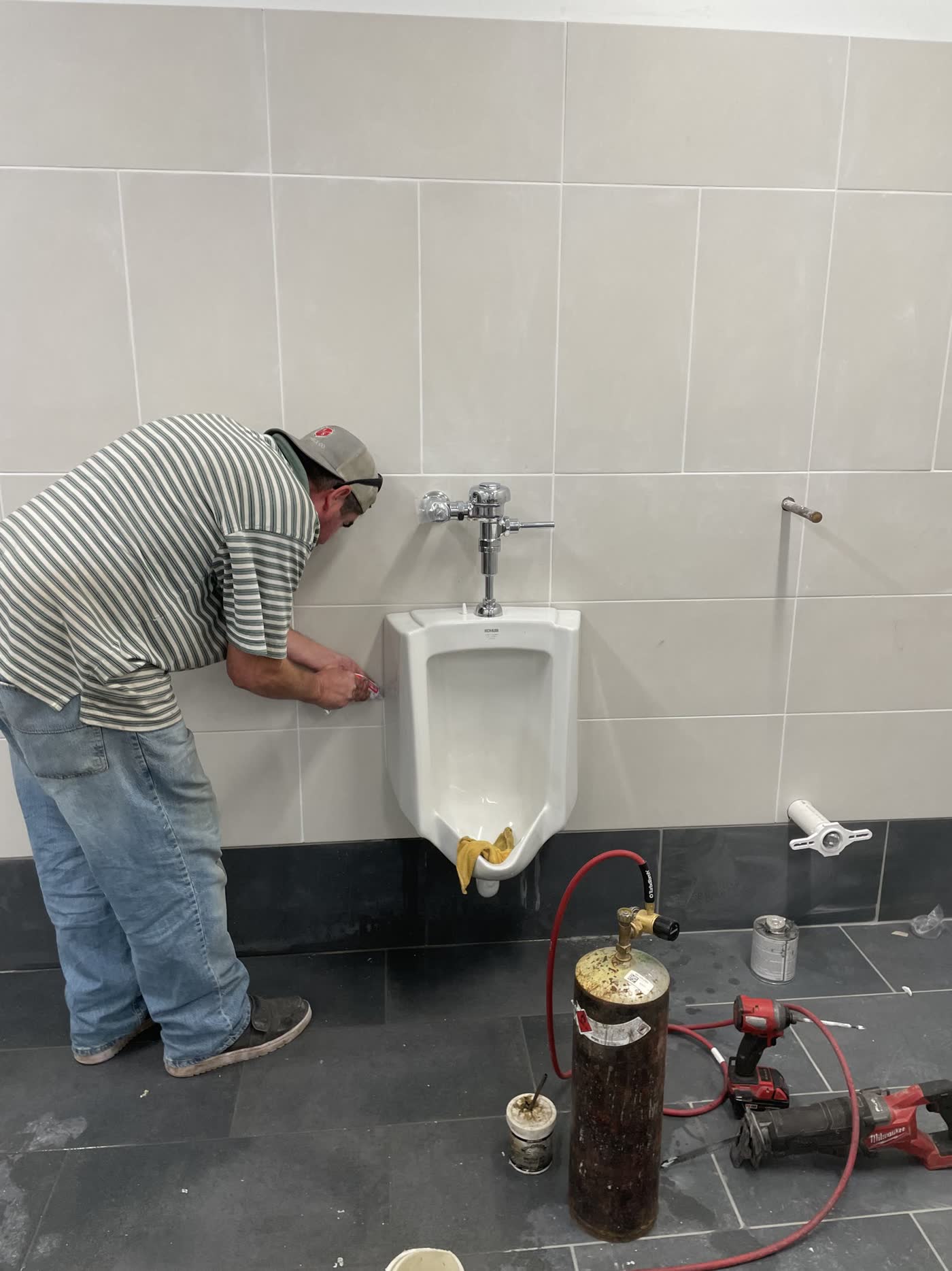 Plumber setting a wall-hung urinal on a commercial restroom job